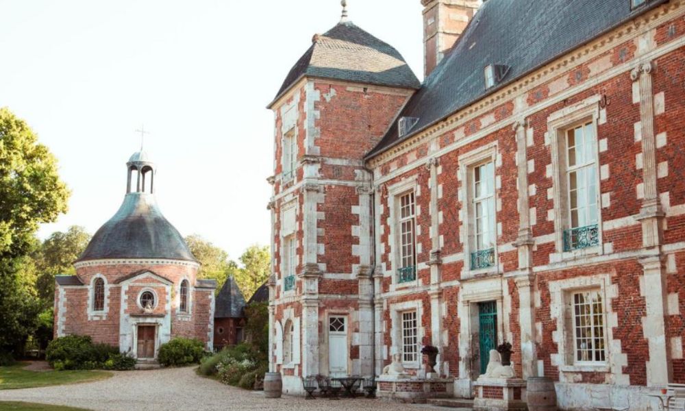This is an image of a red-bricked house with a garden and plenty of bedrooms with windows overlooking the outdoors.
