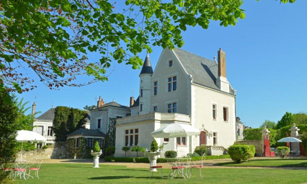 This is an image of a big white chateau with a big green field around it.