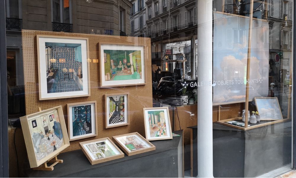 This is an image of an art shop with prints and paintings displayed in the front windows of a shop.