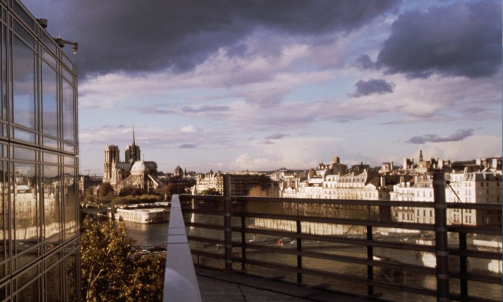 This is an image of an expansive view of Paris from a building's terrace. It is a cloudy day, so the dark clouds make up the top half of the image.
