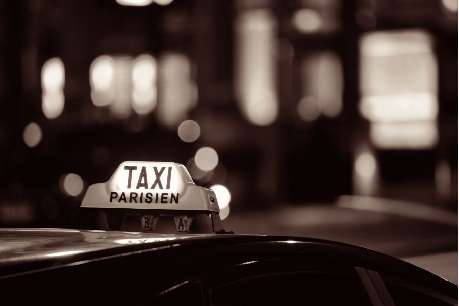 This is an image of a taxi with the light on in Paris.