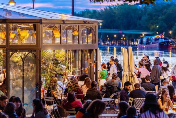 This is an image of a big outdoor deck space with people sitting on tables talking.