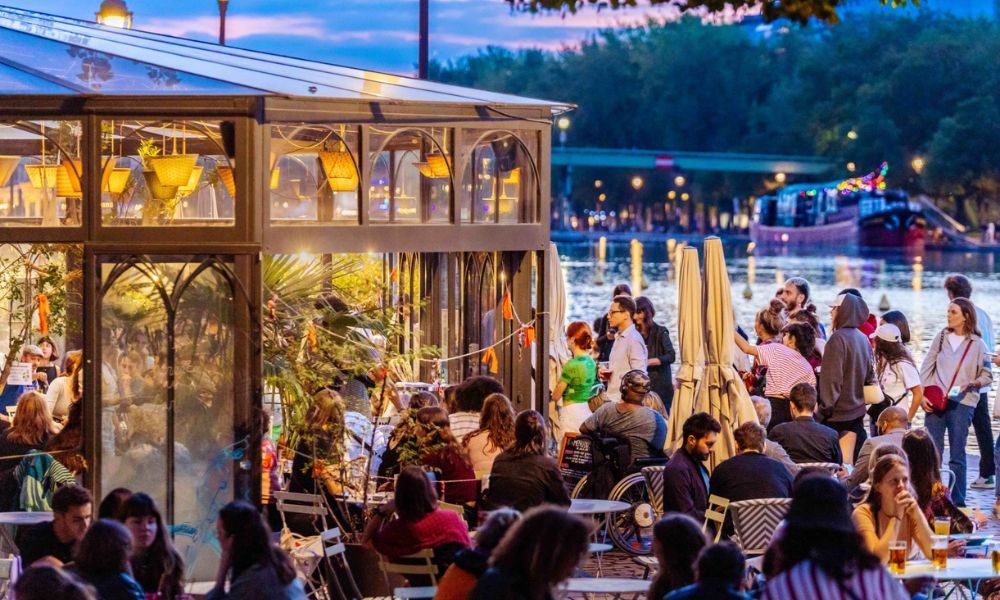 This is an image of a big outdoor deck space with people sitting on tables talking.