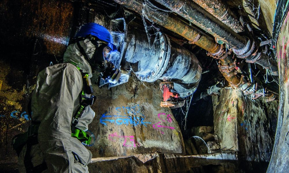 This is an image of a man in a sewer drain in a protective hazmat suit.