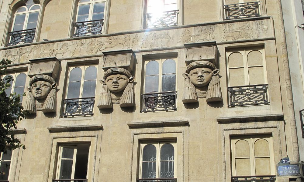 This is an image of the side of a concrete wall that has ancient Egyptian faces carved into the side.