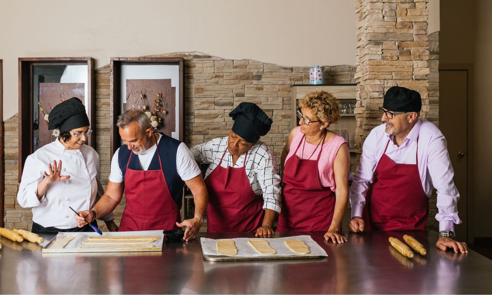 This is an image of a group of people watching a chef roll pastries as part of their cooking class.
