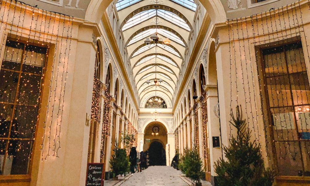 This is an image of a street that os lined with shops and fairy lights and a big ceiling sun light.