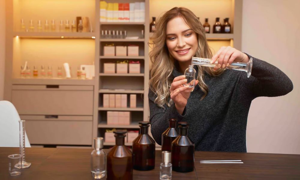 This is an image of a girl pouring perfume from a beaker into a perfume bottle.