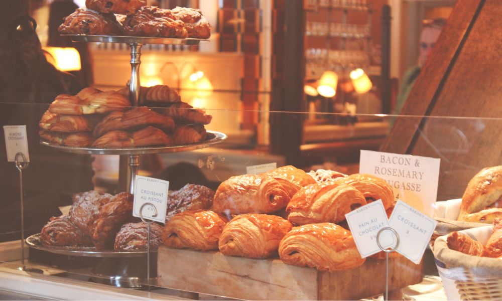 This is an image of a bakery with croissants, pastries and more sitting on the counter.