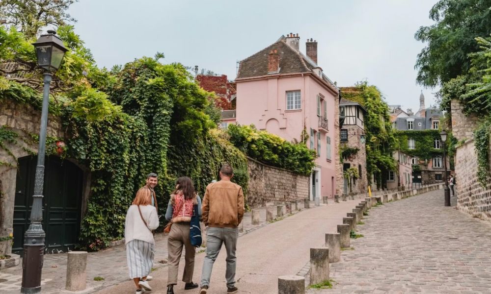 This is an image of a group of people walking up an iconic cobblestone street in Montmartre.