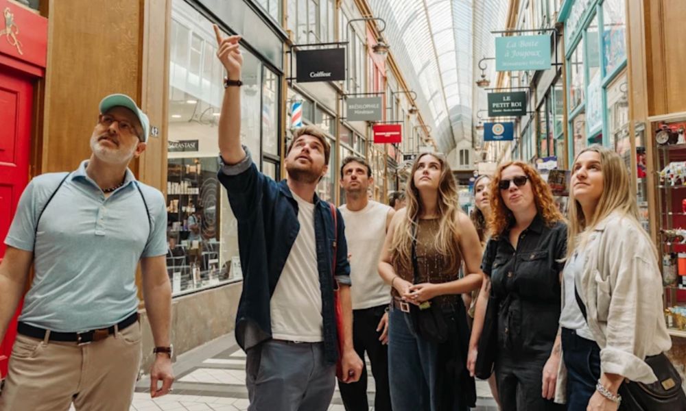 This is an image of a tour group in the city walking around. The tour guide has stopped to point something out and everyone is looking up.