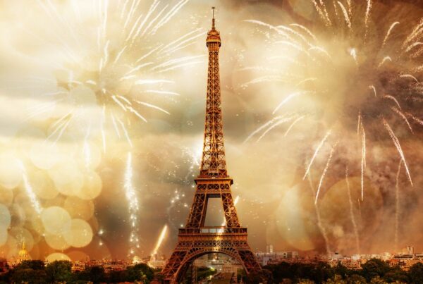 This is an image of the Eiffel Tower in the evening with fireworks all around it.