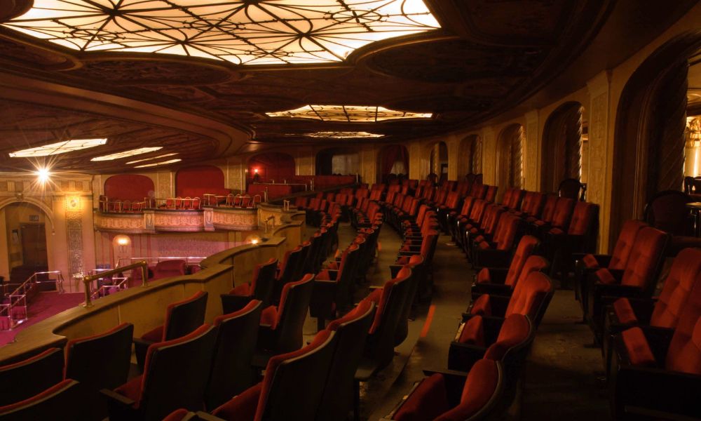 This is an image of an empty theatre with lots of red seats in rows.