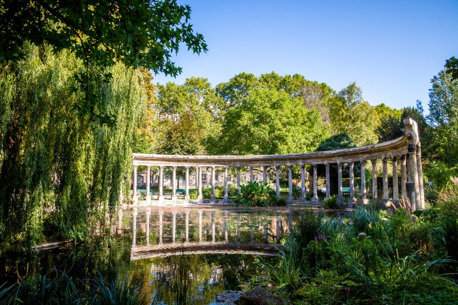 This is an image of a park in Paris with a big ancient ruin in the middle of it.