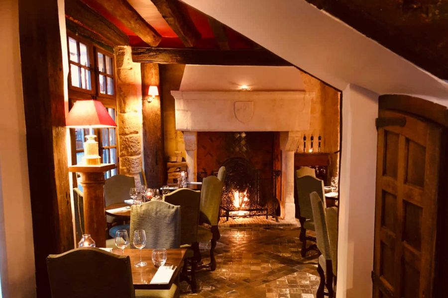 This is a picture of a cosy little bistro with a fire place and small tables arranged around the room.