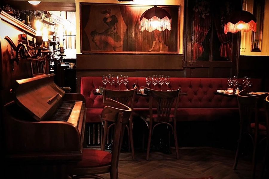 This is an image of a darker, more discreet dining room with velvet seating and dark wood tables and chairs.