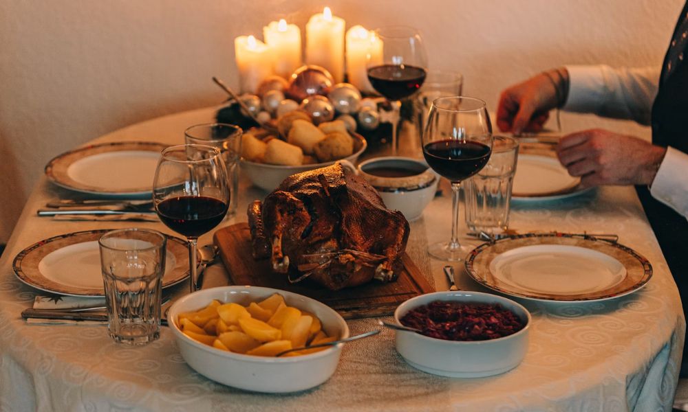 This is an image of a Christmas eve dinner table that has a Christmas feast laid out on it and a Christmas candle.