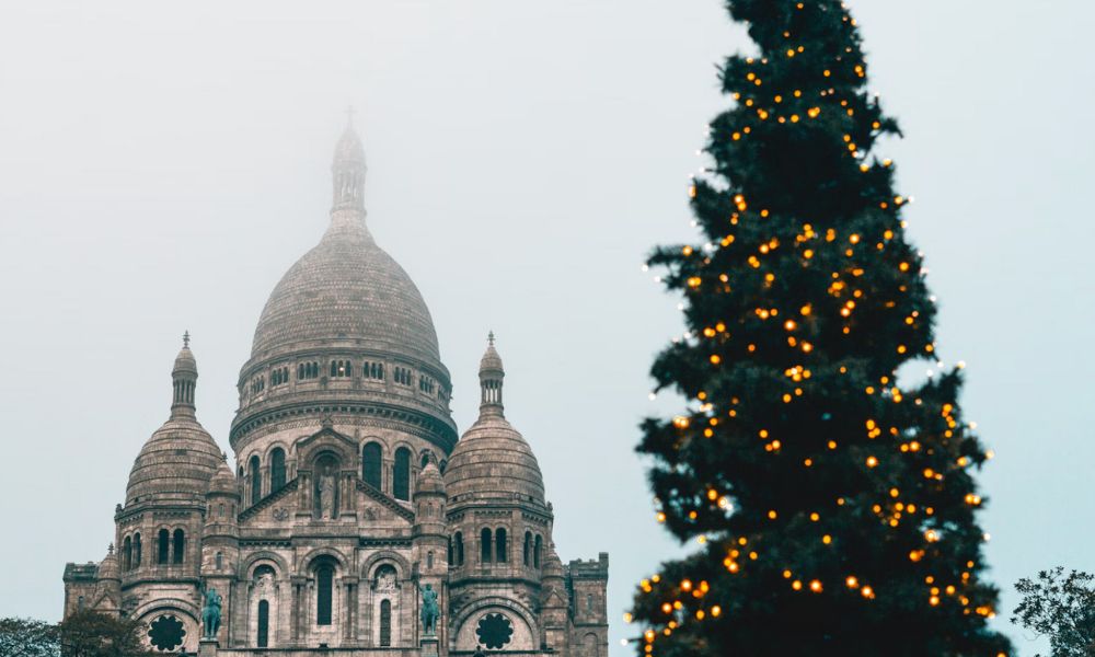 This is an image of Sacre-Coeur in Montmartre with a big Christmas tree out front.