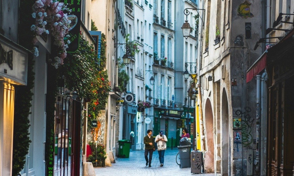 Two people walking along a cobbled street in Paris.