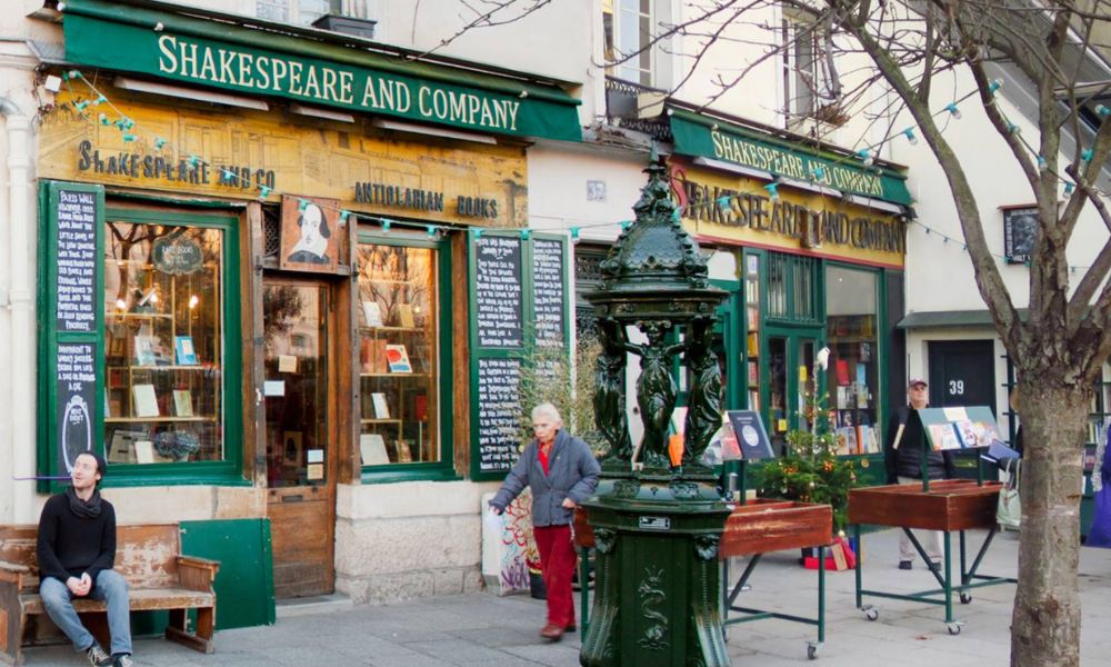 This is an image of a famous bookshop with green-painted exterior, books in the shop window and a seating area outside.
