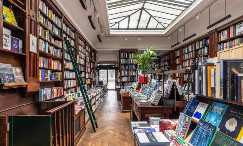 This is an image of a bookstore filled with books lining all the walls and a big skylight at the top on the roof.