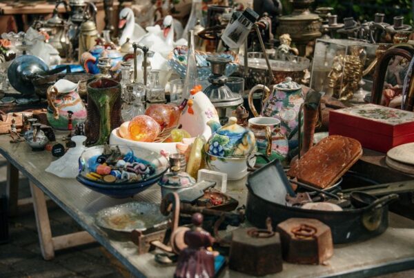 This is an image of a collection of dusty household wares and antiques laid out on a table.