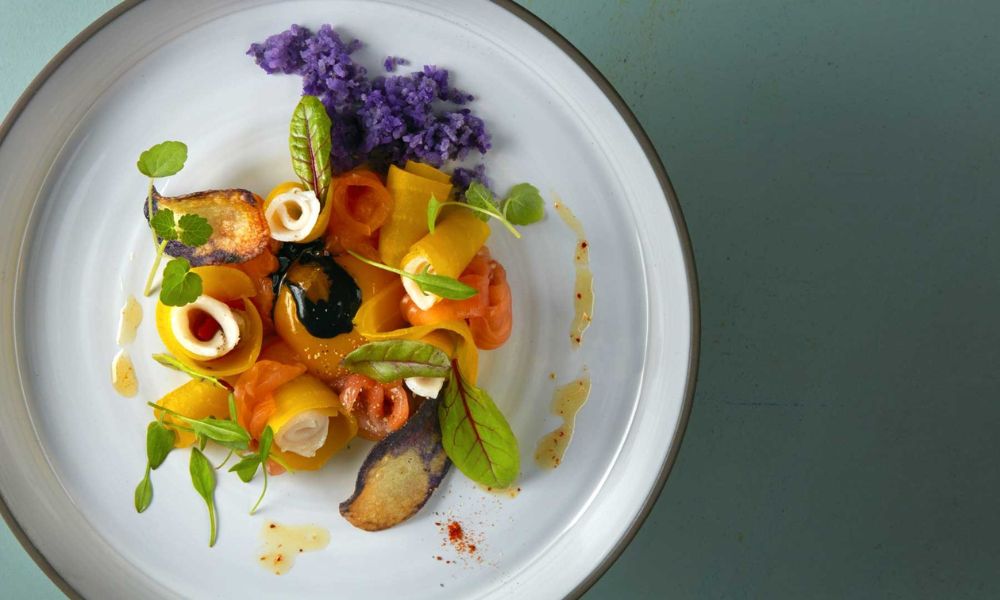 This is an image of a gourmet meal laid out on a plate with flower garnishes.