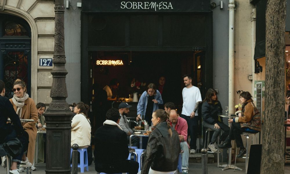 This is an image of a nice wine bar with people sitting outside at tables and talking.