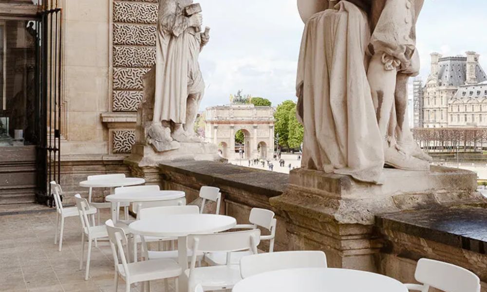 This is an image of a lovely balcony in Paris with tables and chairs looking out on to a beautiful courtyard.