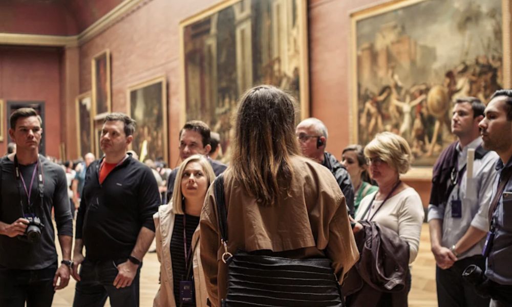 This is an image of a tour group in the Louvre with a guide speaking to everyone.