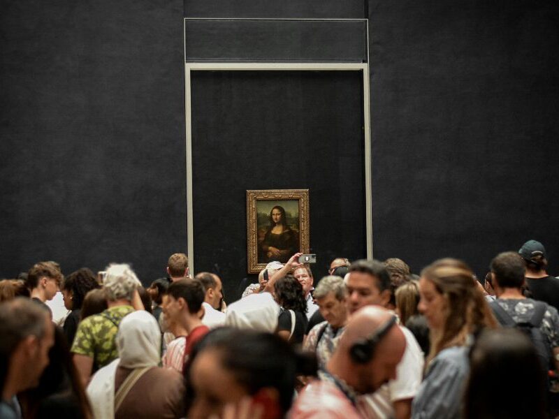 This is an image of everyone crowding around the Mona Lisa and taking pictures / looking at audio guides.