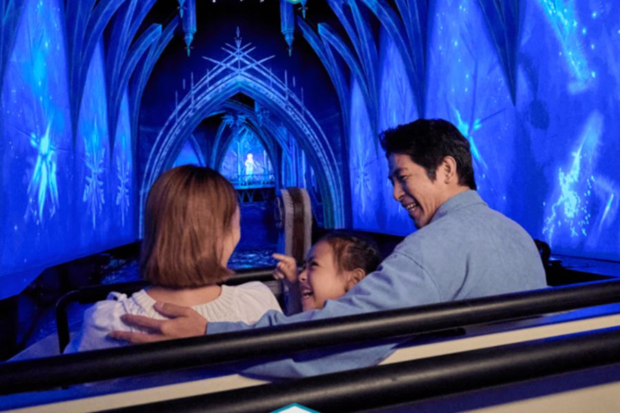 This is a picture of two parents with a kid on a ride in the Frozen World.
