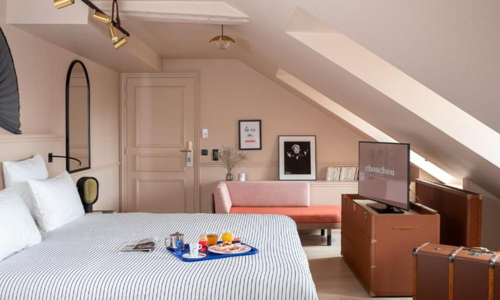 This is an image of a fun quirky and colourful hotel room with pink accents and stripy bed sheets.