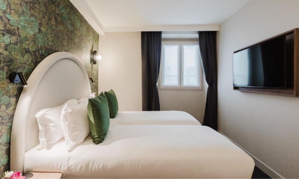 This is an image of a small hotel room with a big double bed and a green feature wall.