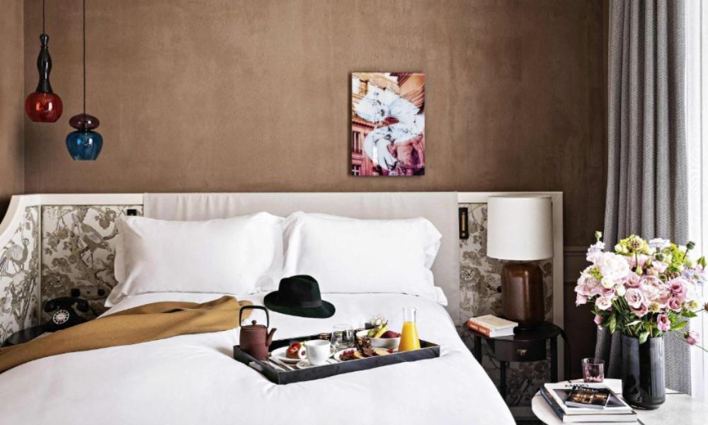 This is an image of a double bed with white sheets and breakfast laying on the bed.