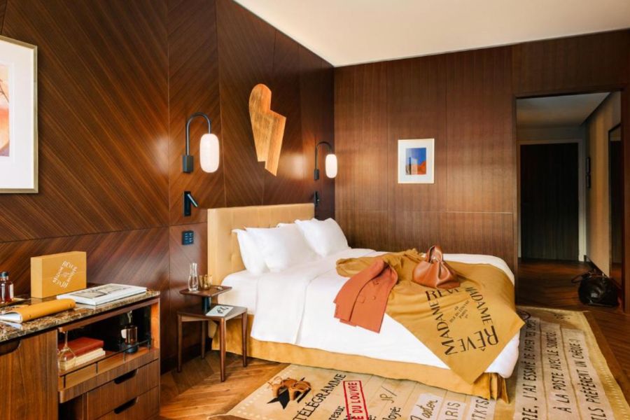 This is an image of a dark, orange room with wooden walls and a double bed with a bunch of different orange decor and art on the walls.