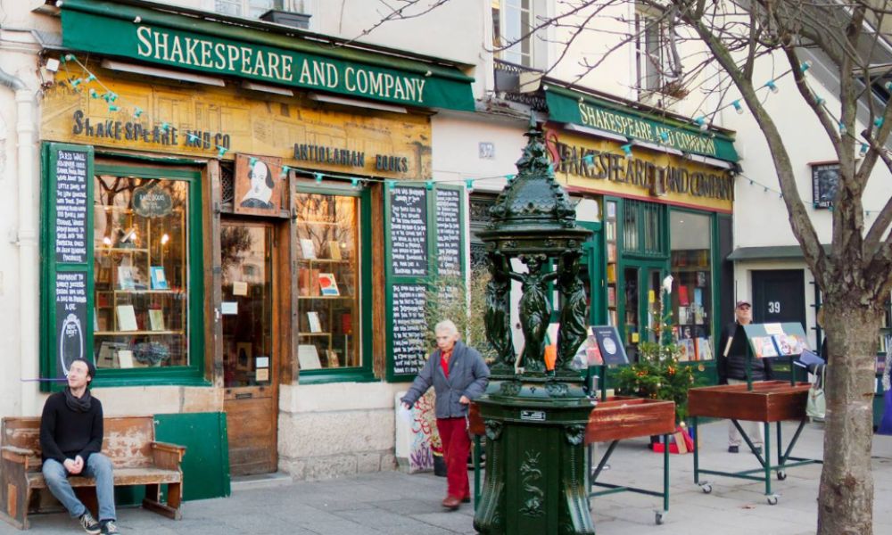 This is an image of an English bookstore with benches outside and a bunch of books in the front glass windows.