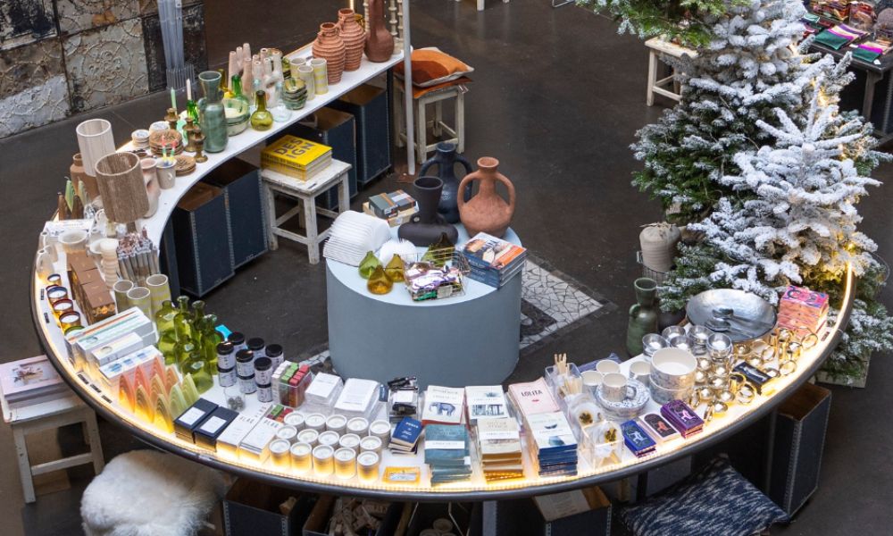 This is an image of a shop with a curved table full of candles and vases and other homewares.