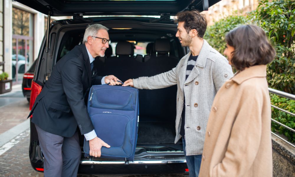 This is an image of a person putting baggage into the back of someone's car.