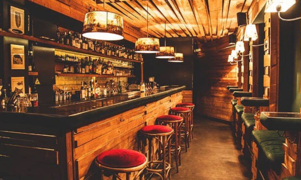 This is an image of a wooden bar with plush seating and overhead lighting.