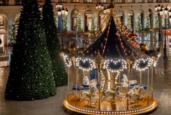 This is an image of a super Chrismassy Square out front of the Ritz in Paris with lit-up Christmas trees and a decorated merry-go-round.