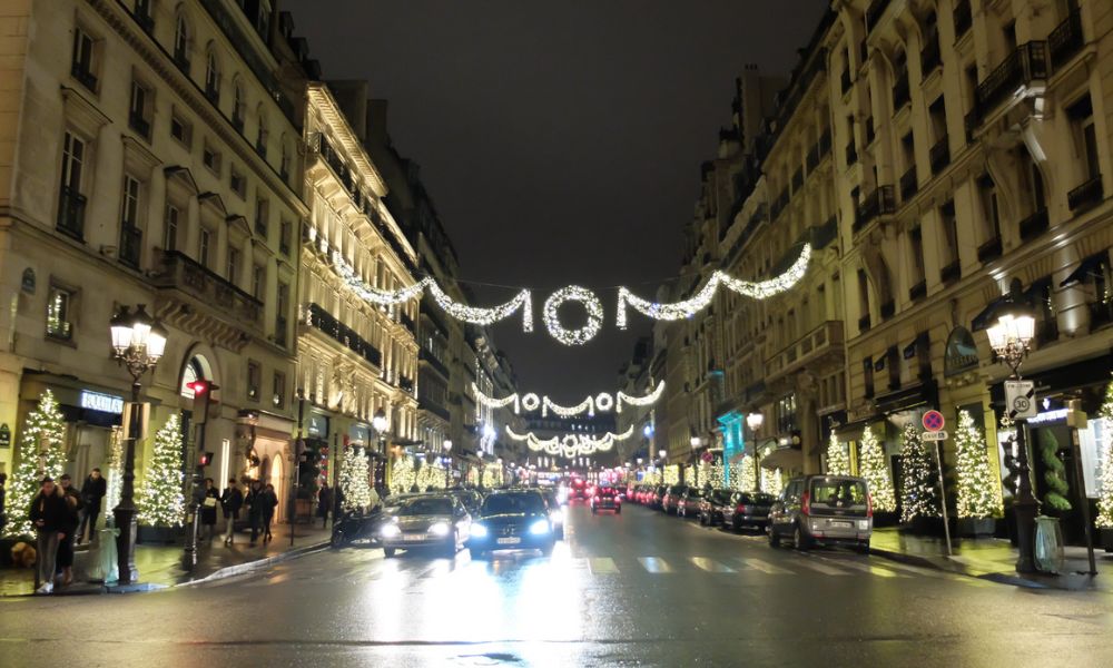 This is an image of a cute street with Christmas lights hanging from building to building.