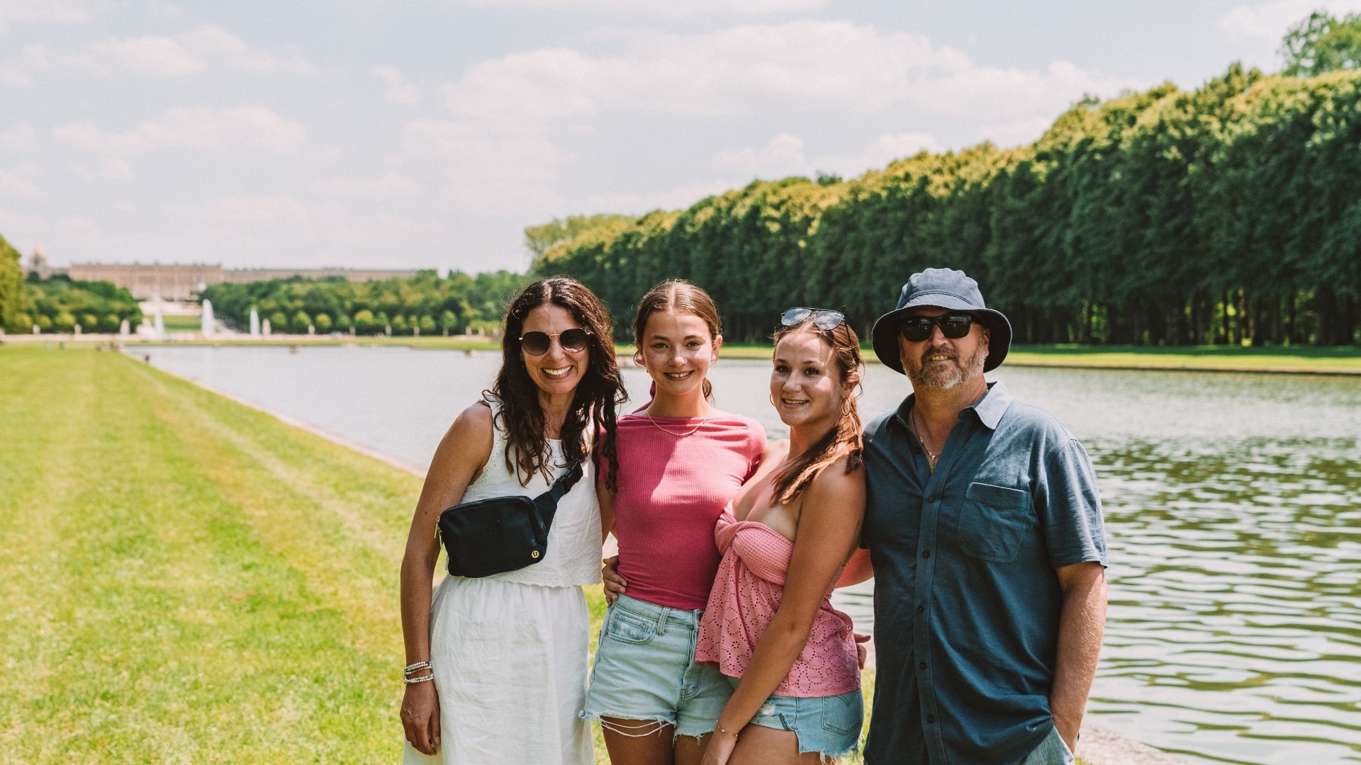 A family made up of a mum, dad and two teenage girls stand in front of the canal posing for photo.
