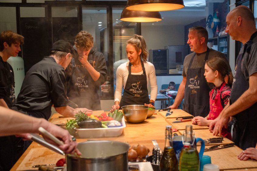 A group of people gathered at a work bench learning to cook in Paris.