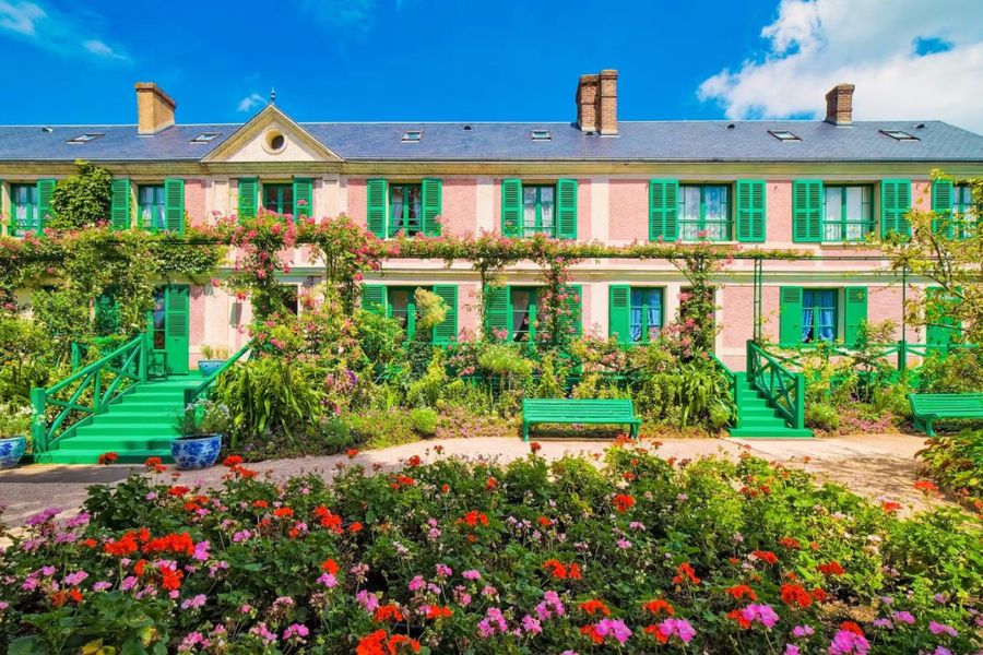 This is an image of Monet's Garden with lots of roses and greenery growing up the house.