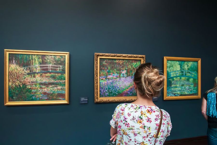 This is an image of a woman looking at a lovely spring painting on the wall.