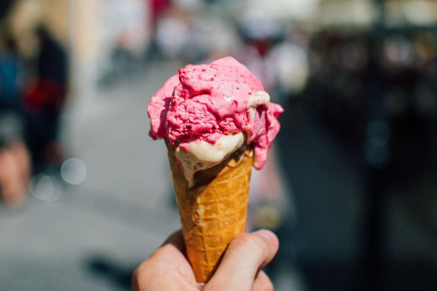 This is an image of someone holding up an ice cream cone with two scoops of ice cream in it. It seems to be hot, so it is melting.