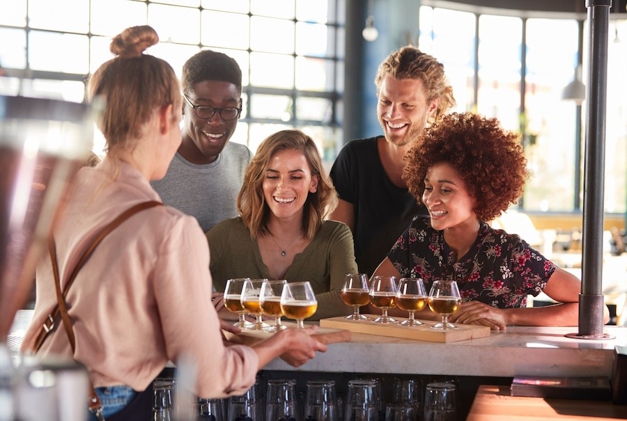 Picture of a group of friends being served a selection of beers on a beer tasting session. This is one of the top Paris Drinking Tours and Experiences to try.