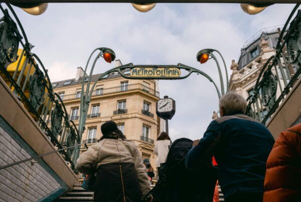 This is an image of commuters exiting the Paris metro. There is a big avantgarde 'Metropolitan' sign on the way out.