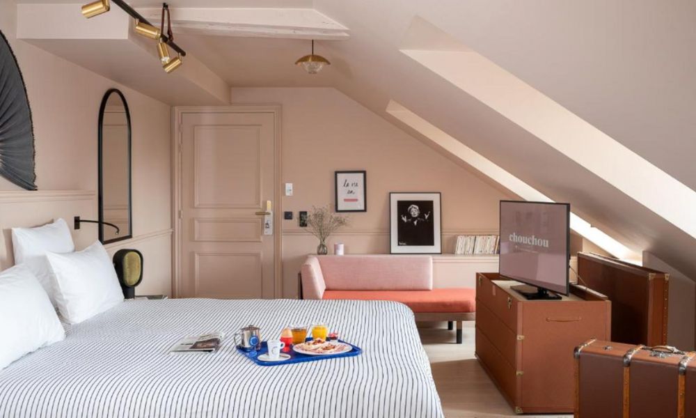 This is an image of a colourful, eccentric hotel room with a double bed, vanity and TV.